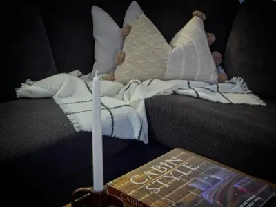 a book sitting on a couch with a blanket and pillows at Modern Townhome at Wintergreen Sauna Steps from Blue Mountain Village in Blue Mountains