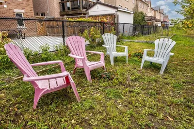 four pink and white chairs sitting in the grass at Walk-out Basement Apartment with Private Entrance in Brampton
