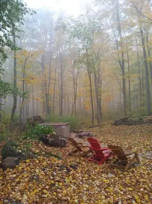 two chairs sitting next to a fire in the woods at Anthropocene Jewel Cottage in Milton