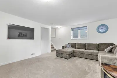 a living room with a couch and a clock on the wall at Modern 1 Bedroom + Den in Cambridge in Cambridge