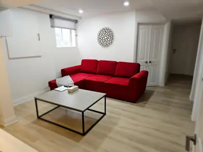 a red couch in a living room with a table at Executive Apartment - 2BDR Parking Self-check in - Walkout basement Lower Unit in Mississauga