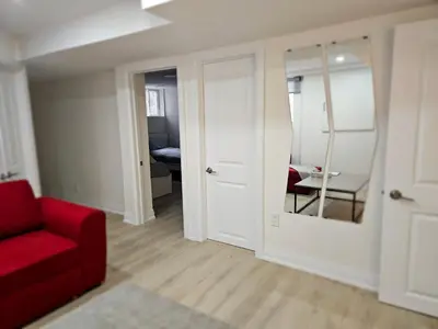 a living room with a red couch and a mirror at Executive Apartment - 2BDR Parking Self-check in - Walkout basement Lower Unit in Mississauga