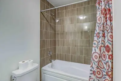 a bathroom with a tub and a toilet and a shower curtain at Modern NEW Build in Caledonia in Caledonia
