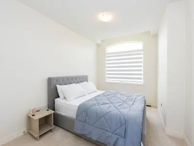 a white bedroom with a bed and a window at Stylish Home in Waterdown in Hamilton