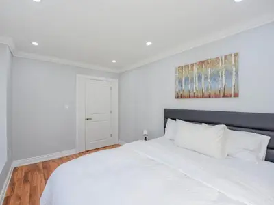 a white bedroom with a white bed and a painting on the wall at Elegant Home in Mississauga in Mississauga
