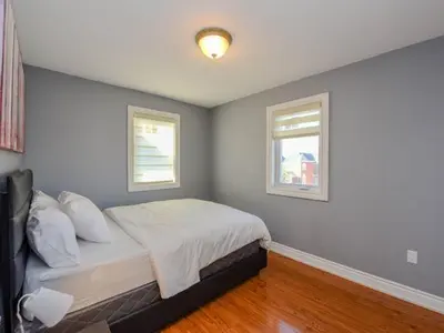 a bedroom with a bed and two windows at Elegant Home in Mississauga in Mississauga