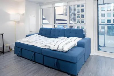 a blue couch in a room with a large window at Chic 1-BR Condo; Parking included; Downtown Core in Toronto