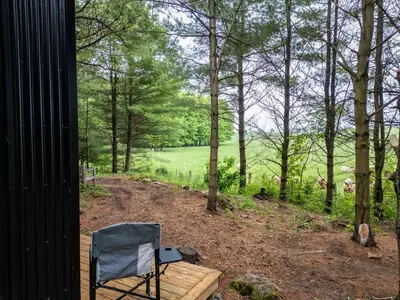 a chair sitting on a porch with a view of a field at Little Cabin in the Pines in Chatsworth