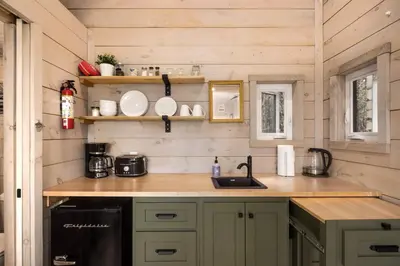 a kitchen in a tiny house with wooden walls at Little Cabin in the Pines in Chatsworth