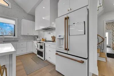 a kitchen with white cabinets and a refrigerator at Sherkston Oasis - Hot Tub Soaks & Luxurious Escape in Port Colborne