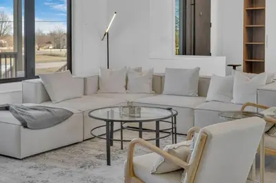 a living room with a white couch and a table at Sherkston Oasis - Hot Tub Soaks & Luxurious Escape in Port Colborne