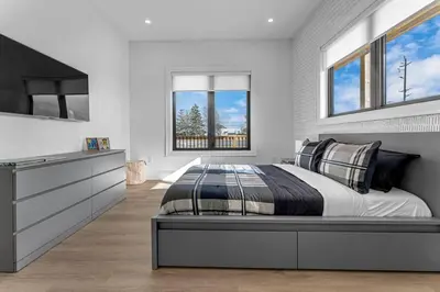 a bedroom with a large bed and two windows at Sherkston Oasis - Hot Tub Soaks & Luxurious Escape in Port Colborne