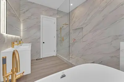 a bathroom with a white tub and a marble wall at Sherkston Oasis - Hot Tub Soaks & Luxurious Escape in Port Colborne