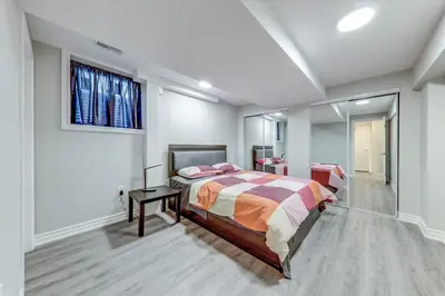 a bedroom with a bed and a mirror at Stunning 7 Br RougeView Home with 2 Kitchens, 5 Bathrooms, Amazing Backyard & 8-Car Parking in Toronto