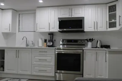 a kitchen with white cabinets and a stove and a microwave at Comfyhome in Vaughan
