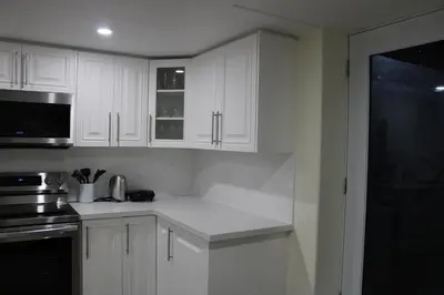 a white kitchen with white cabinets and a microwave at Comfyhome in Vaughan