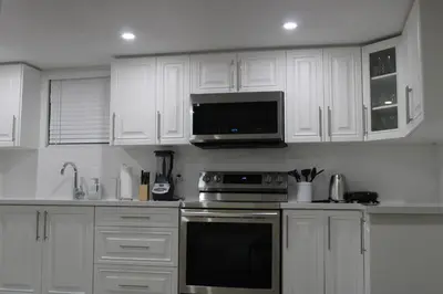 a kitchen with white cabinets and a stove and a microwave at Comfyhome in Vaughan