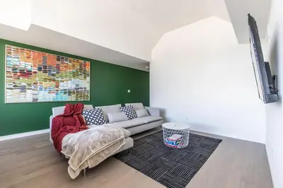 a living room with a white couch and a green wall at Comfortable Lux, Sleeps 10, PingPong, Movie Room in London