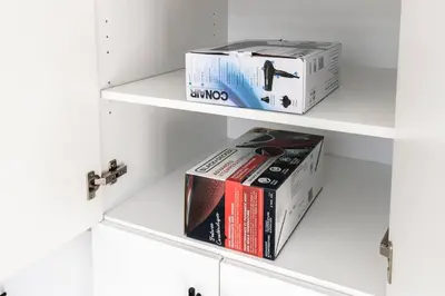 two boxes on shelves in a white cabinet at Comfortable Lux, Sleeps 10, PingPong, Movie Room in London