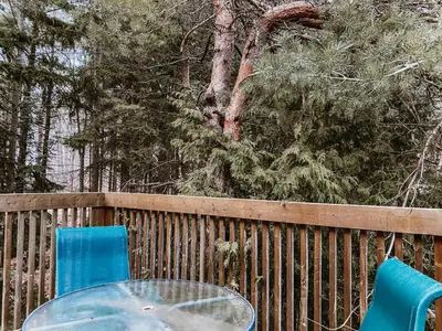 a glass table and two blue chairs on a fence at Irish Mountain Suites in Meaford