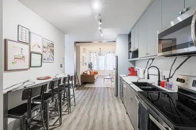a kitchen with white cabinets and bar stools at Downtown Oasis-2BR-Spa Bath-Pet Friendly, Free Parking in Toronto