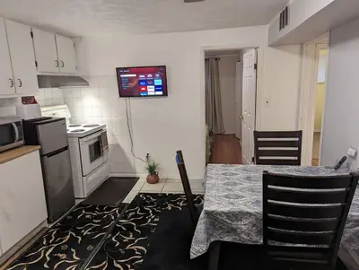 a kitchen with a table and a television on the wall at Cozy basement apartment in the heart of Oakville in Oakville