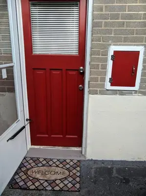 a red door on a brick building with a window at Cozy basement apartment in the heart of Oakville in Oakville