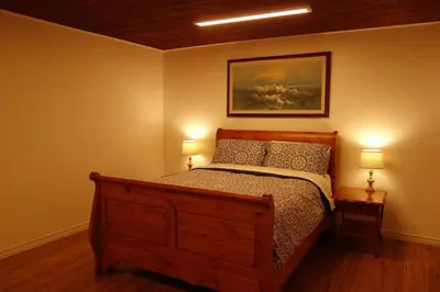 a bedroom with a wooden bed and two lamps at The Nest in the Forest Bed and Breakfast (Hot tub and Sauna) in Lakefield