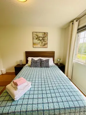 a bedroom with a bed with a blue comforter and a window at Homestay- private room and bathroom in Whitby