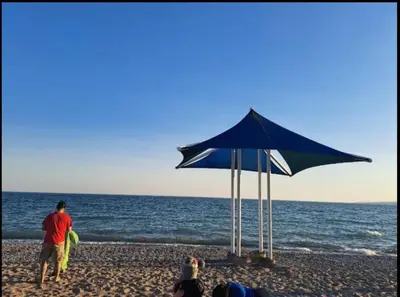 a group of people on a beach with umbrellas at Cozy room near Pickering OPG in Pickering