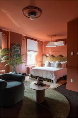 a bedroom with orange walls and a bed and a couch at Hotel Julie in Stratford