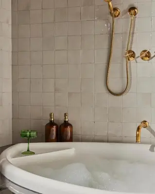 a bath tub with a shower and two bottles at Hotel Julie in Stratford