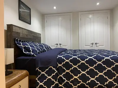 a bedroom with a bed with a blue and white comforter at Cozy Lovely Ravine facing Suite. in Mississauga