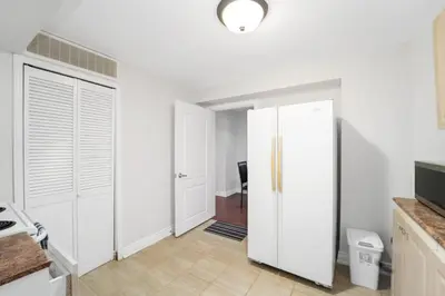 a white kitchen with white cabinets and a door at Cozy Lovely Ravine facing Suite. in Mississauga
