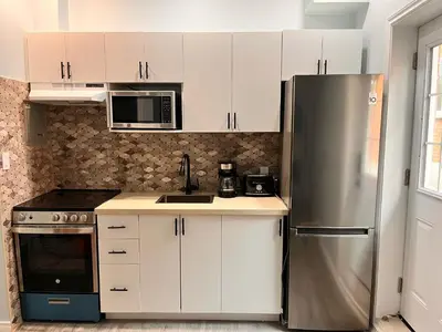 a kitchen with white cabinets and a stainless steel refrigerator at Private Apartment/Suite in Whitby