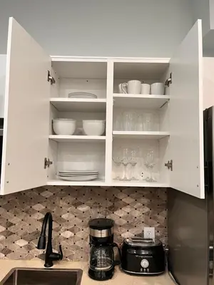 a kitchen with white cabinets with dishes and glasses at Private Apartment/Suite in Whitby