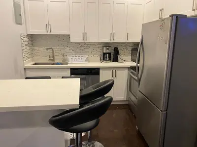 a kitchen with white cabinets and a stainless steel refrigerator at Downtown apartment 2-3 people in Bowmanville