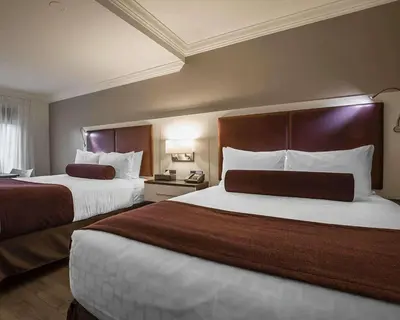 a hotel room with two beds with white and brown at The Saint James Hotel, an Ascend Collection Hotel in Toronto