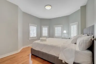 a white bedroom with a large bed and windows at 4-BR Family Haven - Near Wonderland and Vaughan Mills in Vaughan
