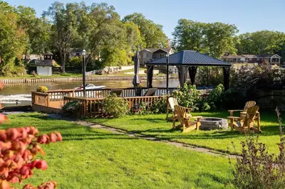 a yard with a gazebo and chairs and a table at Charming riverside cottage, walk to beach in Wasaga Beach