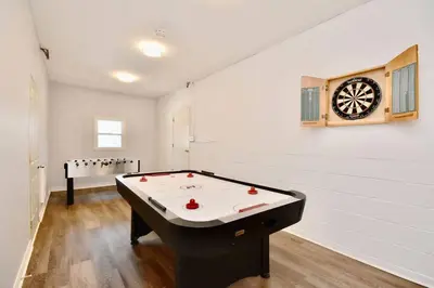 a room with a pool table and a dartboard on the wall at Charming riverside cottage, walk to beach in Wasaga Beach