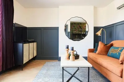 a living room with a orange couch and a mirror at The Dorchester Hotel in Collingwood