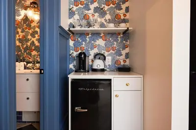 a small kitchen with a black refrigerator and a wallpaper at The Dorchester Hotel in Collingwood