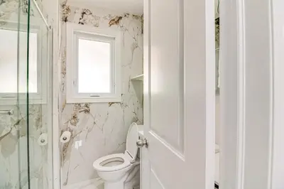 a white bathroom with a toilet and a window at Beautiful house near bluffers beach, 25 minutes to Toronto Downtown, free parking, and wifi in Toronto