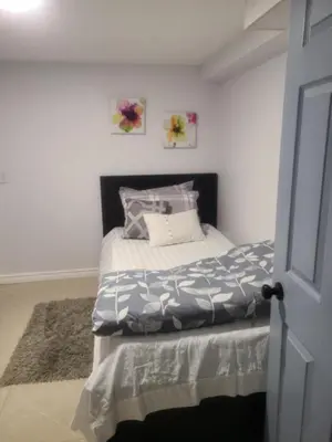 a bedroom with a bed with a gray and white comforter at 2 bedroom + Bath in Eastyork in Toronto