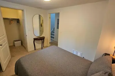 a bedroom with a bed and a mirror and a stool at Modern 2BR Townhouse w Patio & Free Parking Family & Work Stays in Toronto