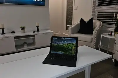 a laptop sitting on a white table in a living room at Modern 2BR Townhouse w Patio & Free Parking Family & Work Stays in Toronto