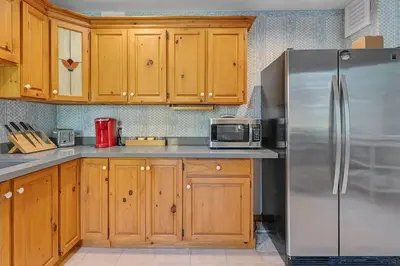 a kitchen with a stainless steel refrigerator and wooden cabinets at Hidden Oasis with Hot Tubs, & Starry Fire Pits in Borden