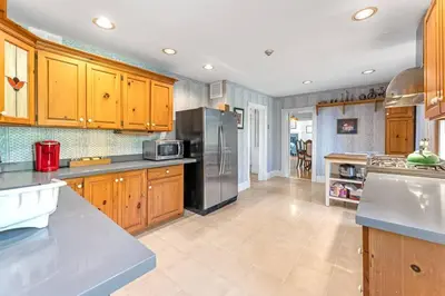 a kitchen with wooden cabinets and a stainless steel refrigerator at Hidden Oasis with Hot Tubs, & Starry Fire Pits in Borden