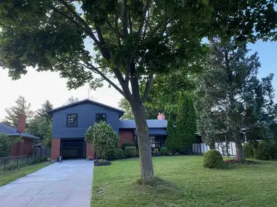 a blue house with a tree in the yard at Vacation paradise in St. Catharines